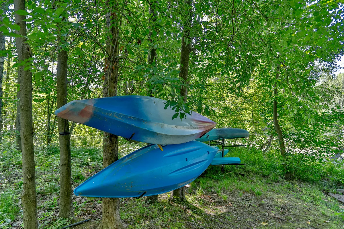 Stacked blue kayaks on wooden racks in forest at Wausau family-friendly house rental