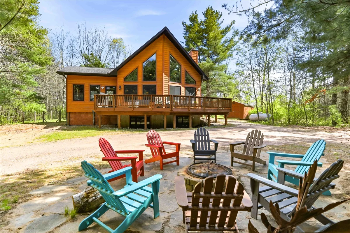 Orange log cabin with deck and fire pit with Adirondack chairs in secluded Wisconsin woods