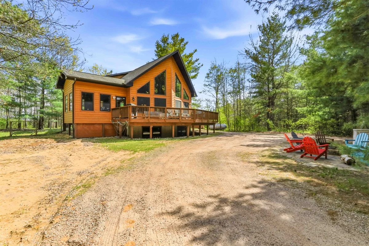 Orange cabin with wrap-around deck and Adirondack chairs in Wisconsin Northwoods forest setting