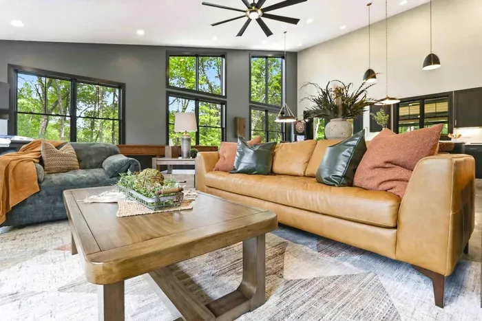 Sink into a warm, sunlit lounge where cozy seating, treetop views, and an easy open layout invite relaxed conversation and connection.