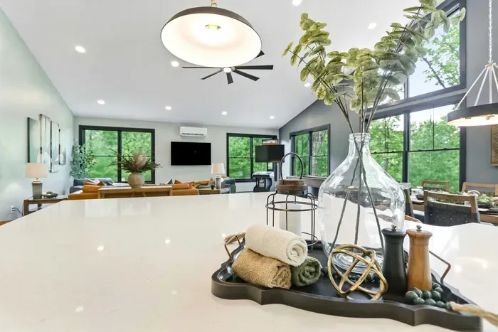 Gather around the oversized island in a bright, treetop-framed space where cooking, dining, and relaxing flow together effortlessly.