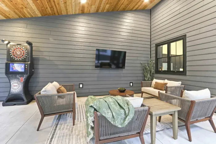 Relax in the screened-in patio with a TV, dartboard game, and cozy seating for laid-back fun.