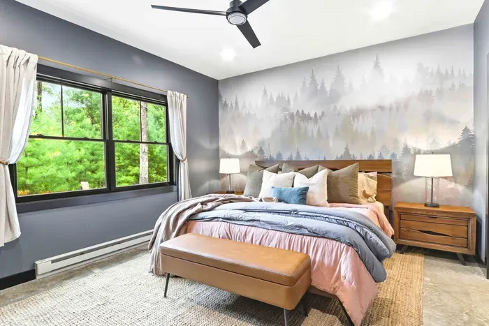 Rest easy in a serene bedroom retreat, where layered textures, soft lighting, and forest views create a calming place to recharge.