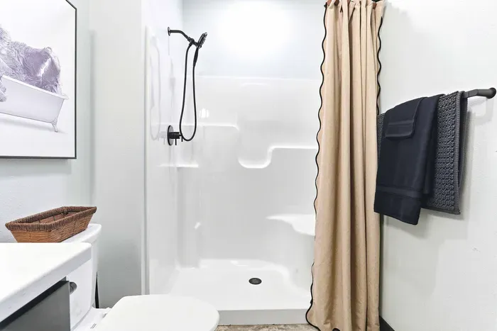 Freshen up with ease in a clean, modern bath featuring a walk-in shower, soft textures, and thoughtful details for a comfortable stay.
