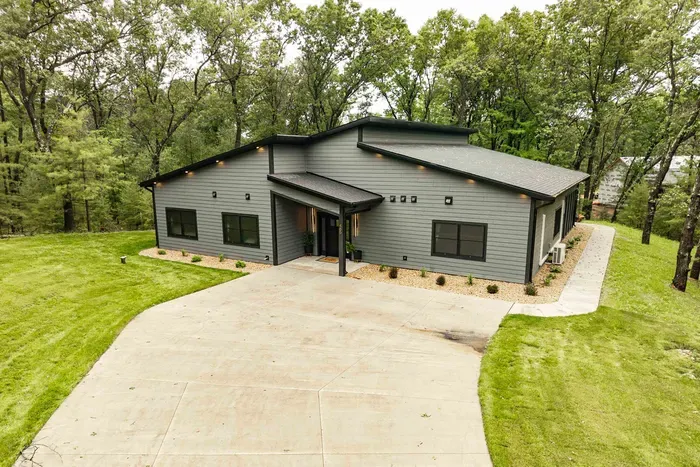 Arrive to a modern wooded retreat with a spacious driveway, welcoming entry, and peaceful surroundings from the moment you pull in.