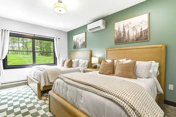 Rest comfortably in a bright double-bedroom retreat with soft layers, warm wood tones, and calming forest views just beyond the window.