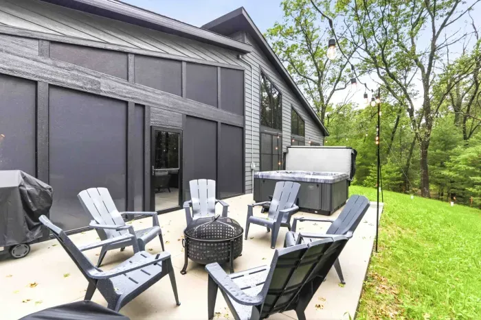 Gather outdoors with the hot tub, grill, and glowing string lights surrounded by peaceful woods.