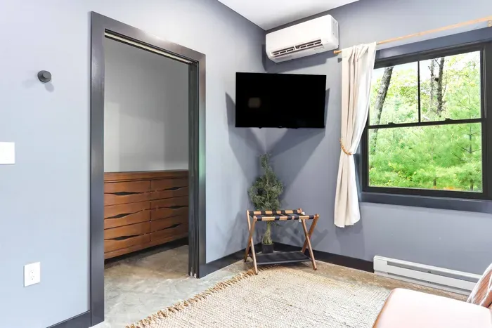 Settle in with a quiet bedroom nook featuring a wall-mounted TV, treetop views, and easy access to storage for a relaxed, comfortable stay.