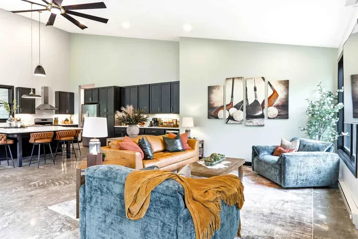 Unwind in a stylish open lounge where cozy textures, warm seating, and a seamless kitchen flow make gathering feel easy and inviting.
