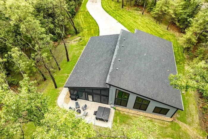 Enjoy the privacy of a wooded escape with a sleek exterior, open lawn, and generous driveway space.