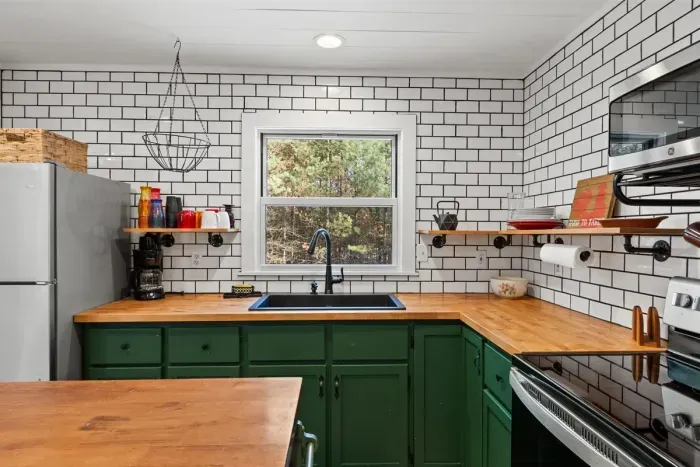 A bright kitchen featuring green lower cabinets, adding a pop of color and a fresh, modern touch to the space.