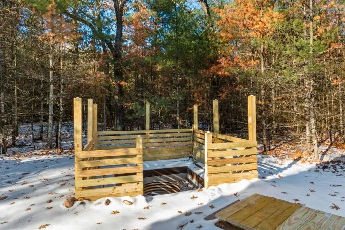 Simple wooden firepit, glowing warmly in a natural backyard setting.