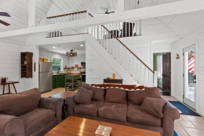 Crisp white walls, a cozy brown sofa, and a staircase adding architectural interest.