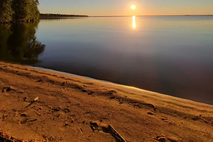 Slow down on the sandy shoreline as the sun sets over calm water, creating a peaceful backdrop for unforgettable lakefront moments.