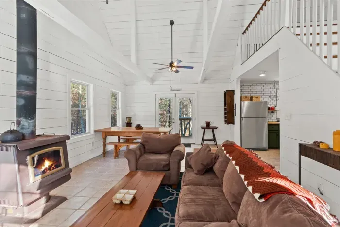Sunlit white walls frame a rich brown couch, with a sleek fireplace anchoring the space.