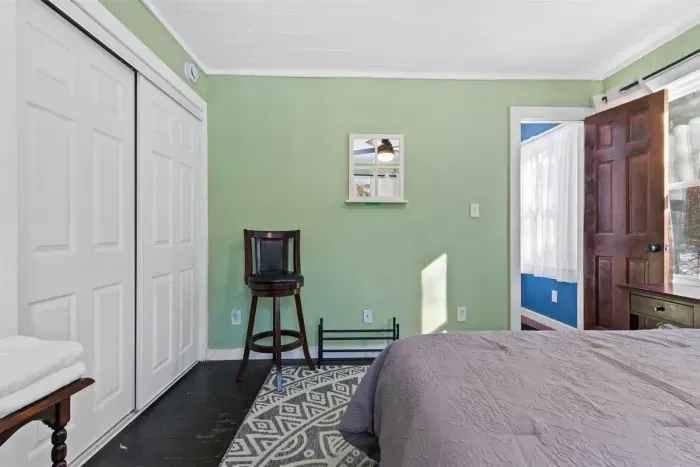 A fresh and calming bedroom with soft gray sheets set against mint green walls, creating a soothing and inviting retreat.