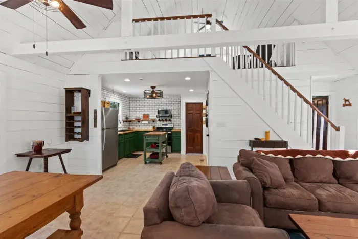 White walls, a plush brown sofa, and stairs creating depth and flow.