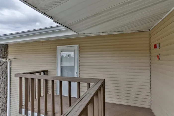 Covered exterior entry with private balcony access, offering a sheltered and welcoming approach to the home.