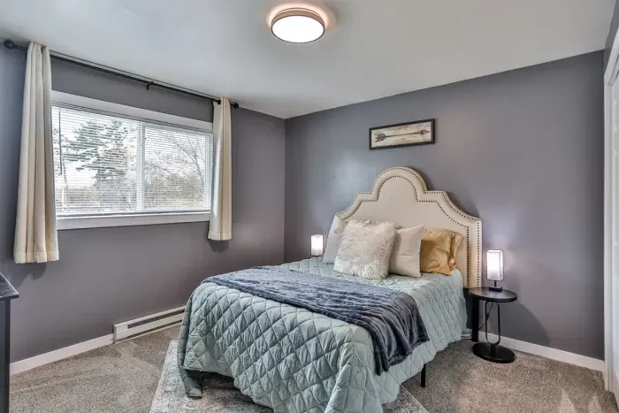 Well-styled bedroom retreat with warm wood furniture, cozy layered bedding, and neutral accents that create a relaxed, restful feel.