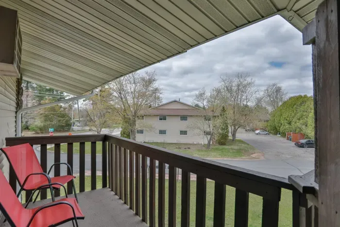 Covered balcony with seating space, offering a comfortable spot to relax and enjoy the neighborhood views.