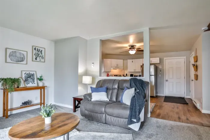 Inviting and well-appointed living area with soft natural light, cozy carpeting, and an open sightline into the kitchen for easy everyday living.