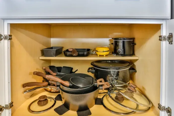 Spacious kitchen cabinet storage stocked with cookware, small appliances, and essentials for convenient meal preparation.