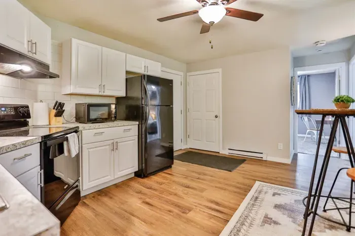 A modern kitchen equipped with high-end appliances and ample lighting. It has a coffee maker, oven, stove top, utensils, and all it takes to fix a delicious meal.