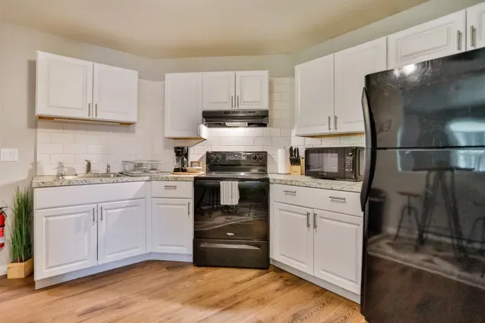 A modern kitchen equipped with high-end appliances and ample lighting. It has a coffee maker, oven, stove top, utensils, and all it takes to fix a delicious meal.