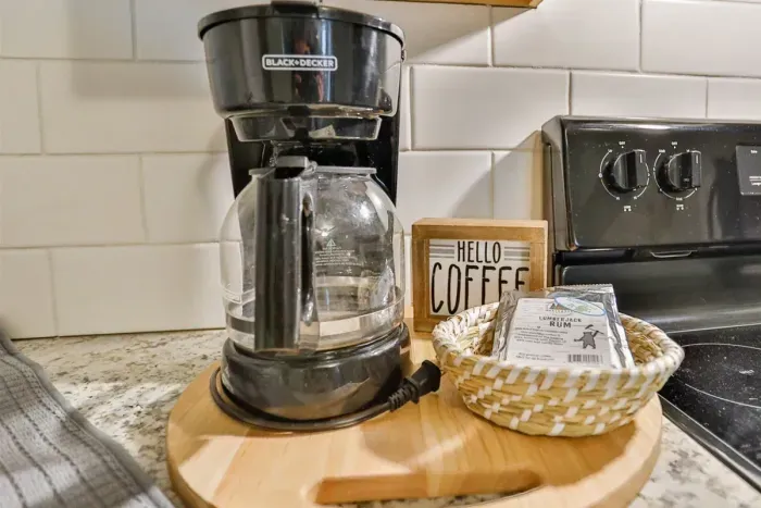 A modern kitchen equipped with high-end appliances and ample lighting. It has a coffee maker, oven, stove top, utensils, and all it takes to fix a delicious meal.