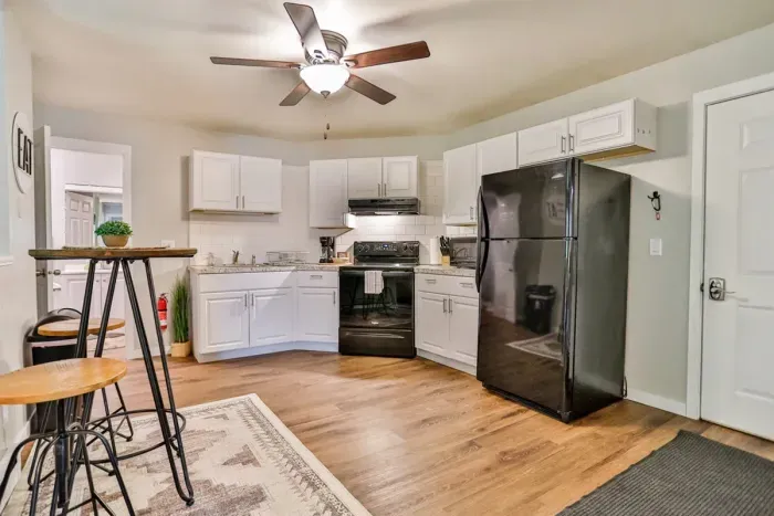 A modern kitchen equipped with high-end appliances and ample lighting. It has a coffee maker, oven, stove top, utensils, and all it takes to fix a delicious meal.