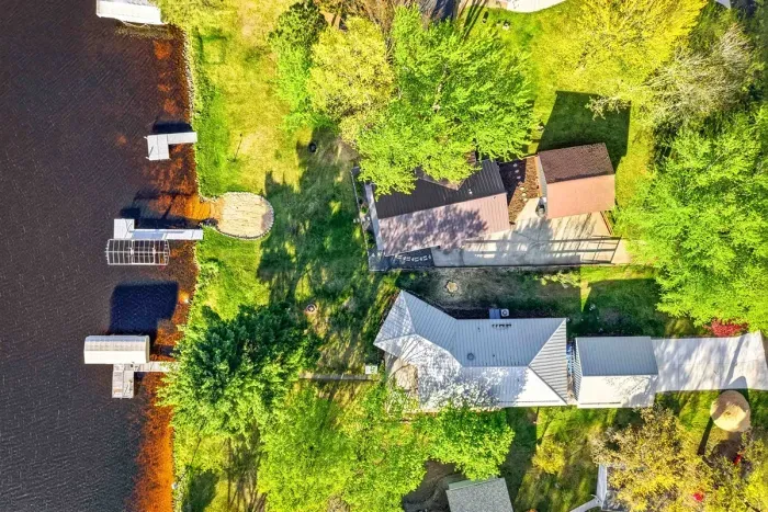 Scenic top-down waterfront perspective highlighting the property’s lakeside setting, mature trees, nearby docks, and peaceful residential surroundings.