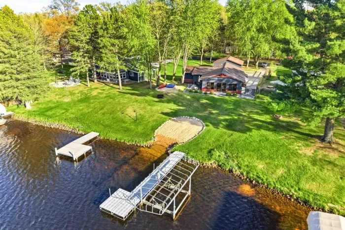 Scenic waterfront setting with open lawn space, sandy beach access, and docks ready for relaxing, swimming, or enjoying lake days.