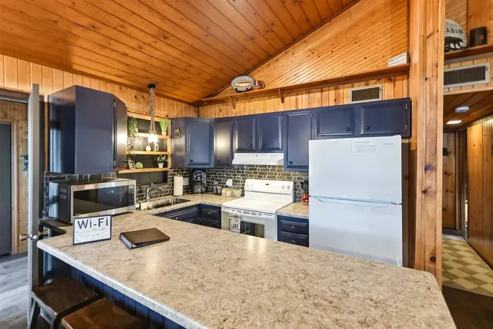 Cozy cabin-style kitchen with blue cabinetry, warm wood walls, and generous counter space for easy meal prep and casual dining.