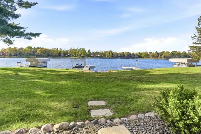 Serene lakefront escape featuring open yard space, landscaped edges, and a picturesque view of the water.
