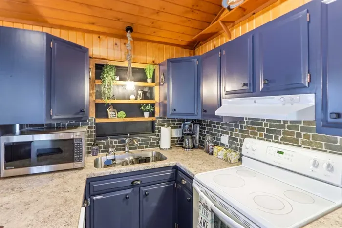 Compact cabin kitchen with blue cabinetry, warm wood finishes, and practical counter space for easy everyday cooking.