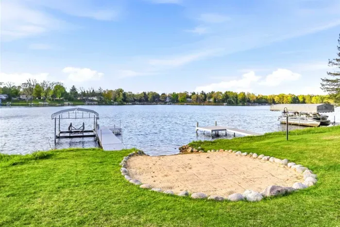 Scenic waterfront setting featuring a spacious lawn, mature trees, and easy access to the lake and docks.