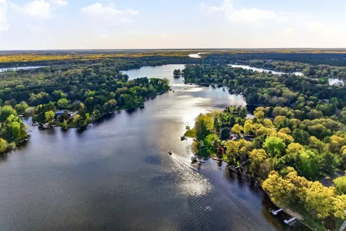 Beautiful lakefront perspective highlighting the property’s shoreline location and surrounding forested views.