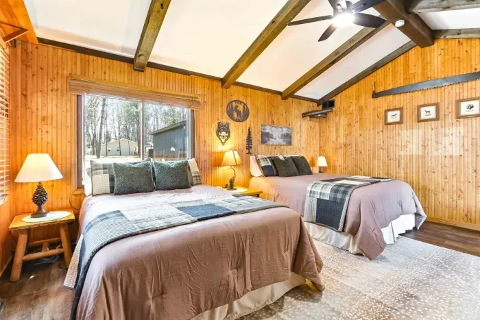 Rustic cabin-style room with 2 comfortable queen beds, large windows, and cozy vibes, ideal for group stays or work trips.