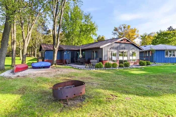 Inviting waterfront cottage featuring updated siding, expansive windows, and a peaceful setting surrounded by mature trees.