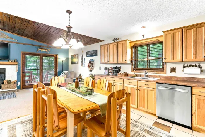 Gather for home-cooked meals in a fully equipped kitchen featuring stainless steel appliances and plenty of counter space. Share stories and morning coffee around the log-style dining table, surrounded by warm wood tones and charming cabin accents.