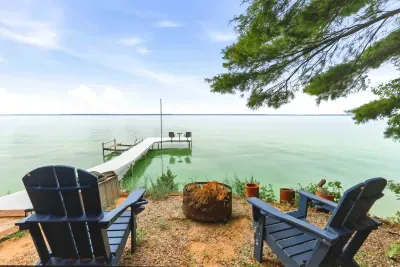 Take in panoramic lake views from the two Adirondack chairs and private dock featured at this property. Enjoy serene mornings or relaxing sunsets by the outdoor fire pit, which adds to the tranquil, natural atmosphere perfect for unwinding.