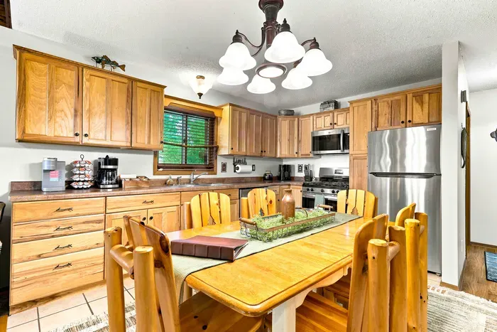 Enjoy effortless meal prep in a classic cabin kitchen equipped with stainless steel appliances and abundant cabinetry. Unwind together over dinner at the rustic wood dining table right at the heart of the home.