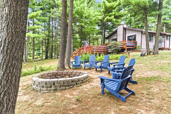 Unwind around the large stone fire pit with plenty of Adirondack chairs for the whole group, set against a scenic backdrop of pine trees and the spacious wooden deck.