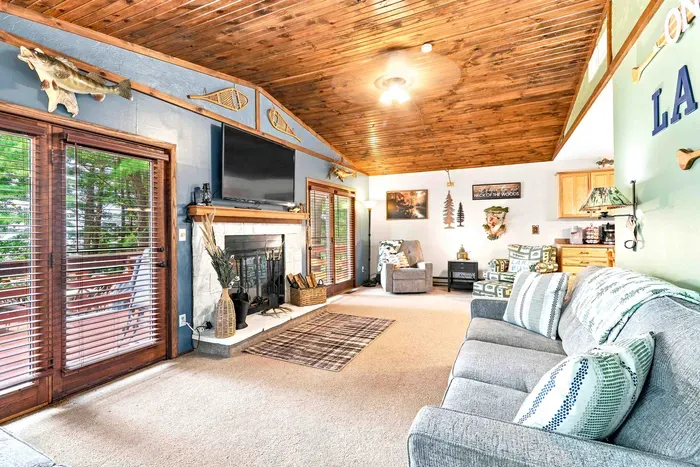 Bask in the warm, inviting atmosphere of this open-concept main living area, complete with soaring vaulted wood ceilings and direct access to the deck. Gather around the cozy stone fireplace, catch the big game on the flat-screen TV, or unwind in plushseat