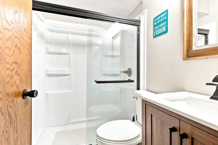 Clean up effortlessly after a day of outdoor adventures in a bright, modern bathroom equipped with a walk-in shower, a modern vanity with cabinet storage, and stylish rustic decor.
