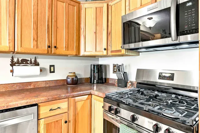 Cook up delicious home-style feasts with ease thanks to the full suite of stainless steel appliances, including a gas oven and stovetop. Ample counter space and a nearby wooden dining set make serving and gathering a breeze.