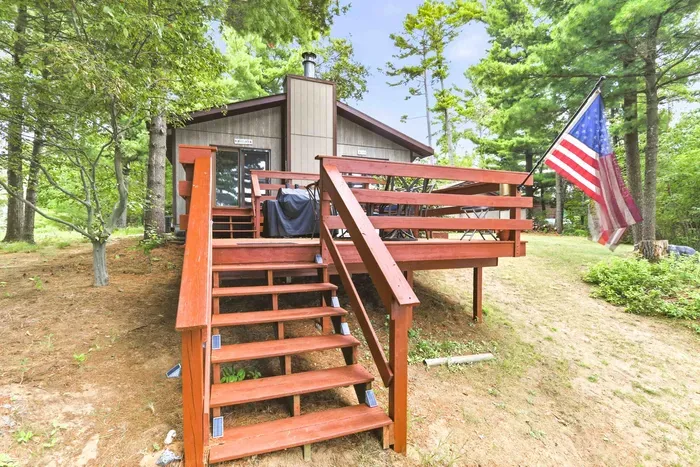 Step up to outdoor living on the spacious wooden deck, equipped with a gas grill and patio dining set for sunny barbecues surrounded by nature.