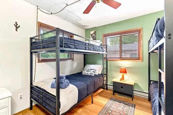 Maximize sleeping space without sacrificing comfort in this charming, nature-inspired bedroom. Equipped with two sturdy bunk beds, soft plush linens, and a quiet ceiling fan, it’s an inviting retreat for a restful night's sleep.
