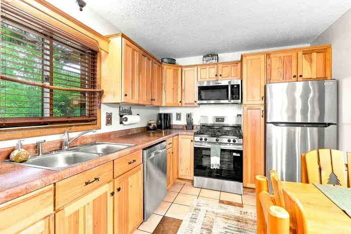 Enjoy peaceful views of the surrounding greenery while washing up at the double sink in this fully equipped cabin kitchen. Modern stainless steel appliances, including a gas range and built-in microwave, make preparing your favorite vacation meals effortle
