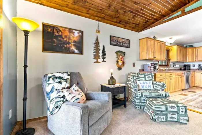 Relax in a cozy reading corner framed by warm wood ceiling panels and charming cabin decor. Curl up in the plush recliner or put your feet up on the matching armchair with ottoman while enjoying ambient glow from the floor lamp, creating the ultimate nook